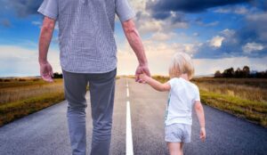 dad holding child's hand walking down the road