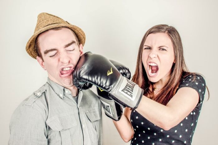 woman punching a man wearing brown cap